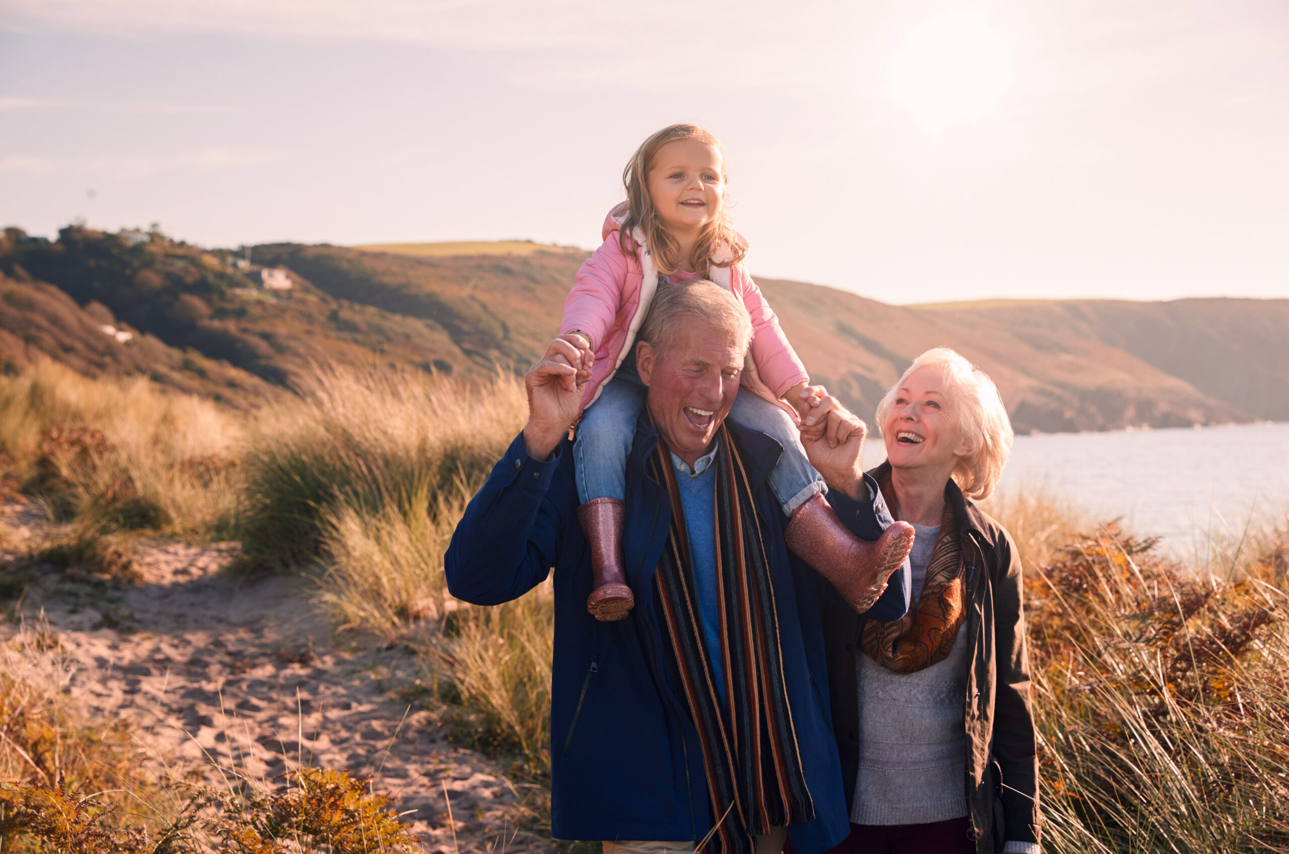 Grandfather,Giving,Granddaughter,Ride,On,Shoulders,As,They,Walk,Through